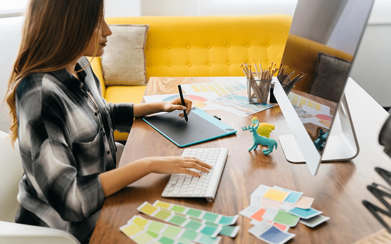 A freelance web designer in a cozy home workspace, surrounded by design sketches and motivational items, symbolizing self-advocacy.