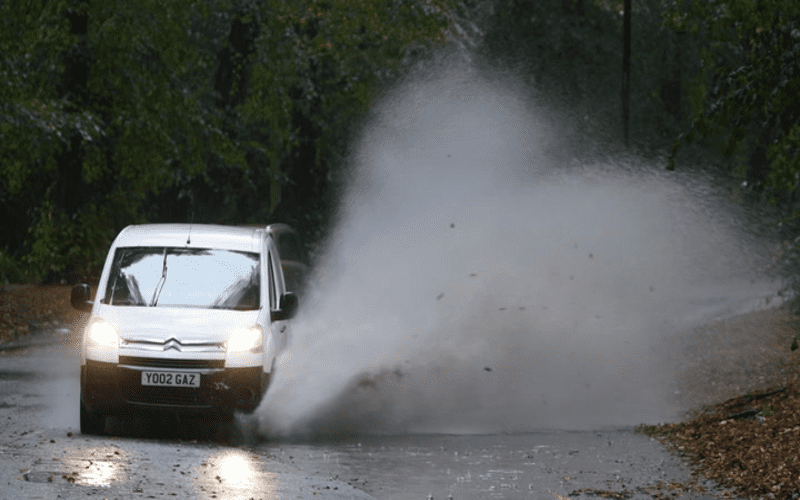 A digital illustration of a programmer in a rainy UK city, coding with a backdrop of CSS elements and corner-shape backgrounds.